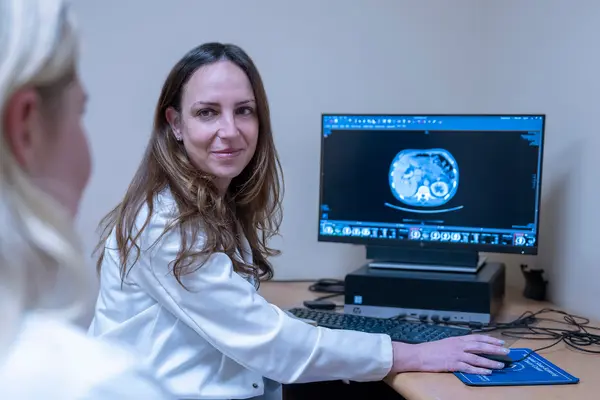 MSK gastroenterologist Dr. Robin Mendelsohn sits at a computer and reviews an imaging scan with an MSK colleague. 