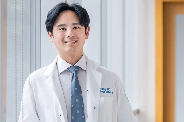 Head and neck medical oncologist Dr. Michael Hwang, in white doctors' coat, sees patients at MSK on Long Island.