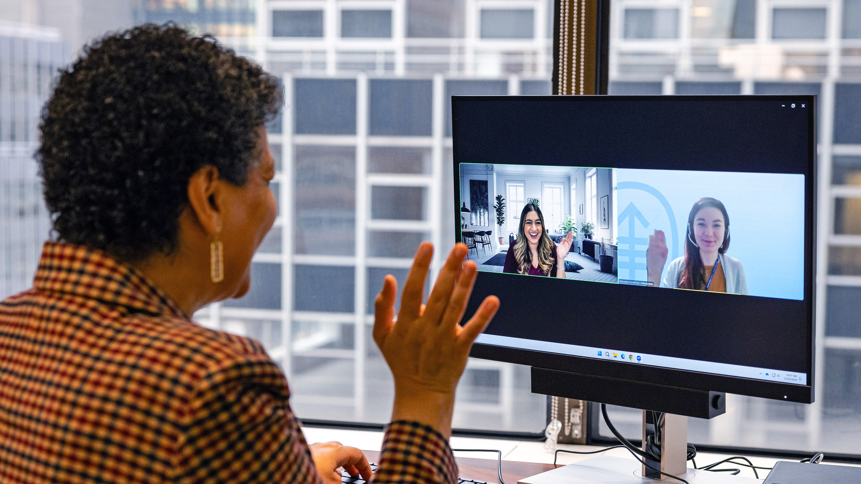 An MSK patient waves at her MSK healthcare providers, seen in a video on a computer monitor during a telemedicine visit. 