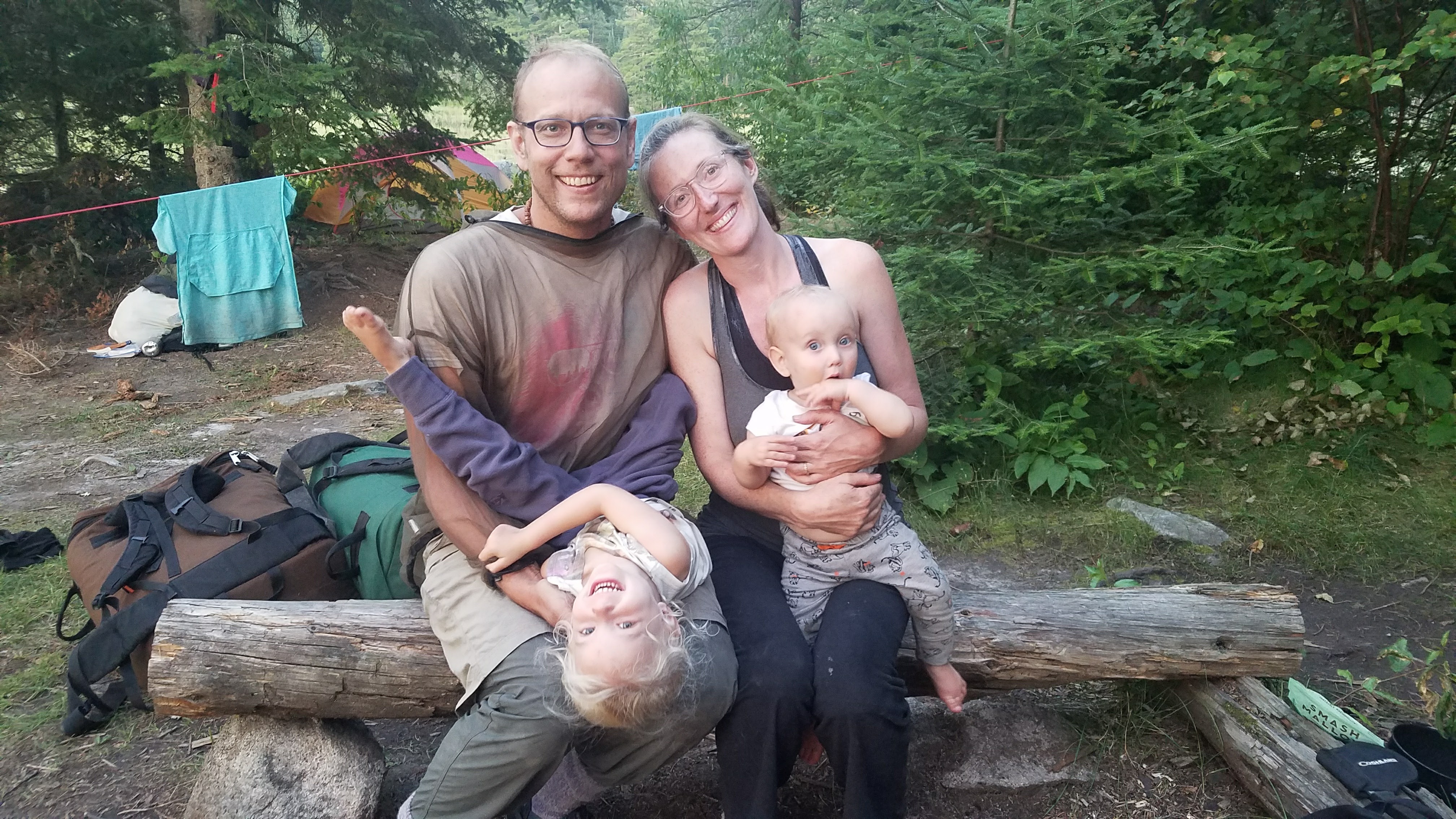 Man and woman posing with their two small children at a campsite