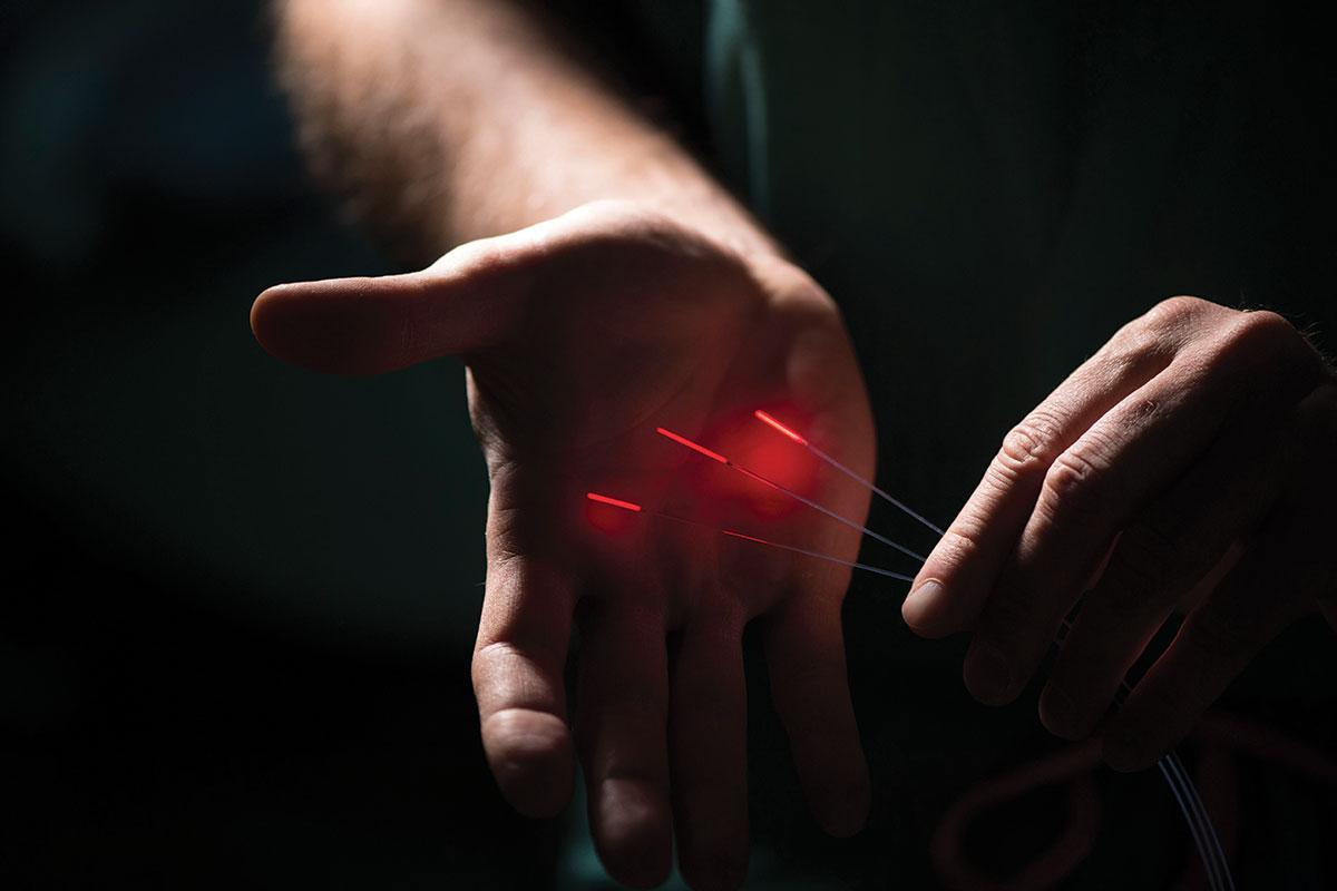 Three illuminated sticks pointed at a hand