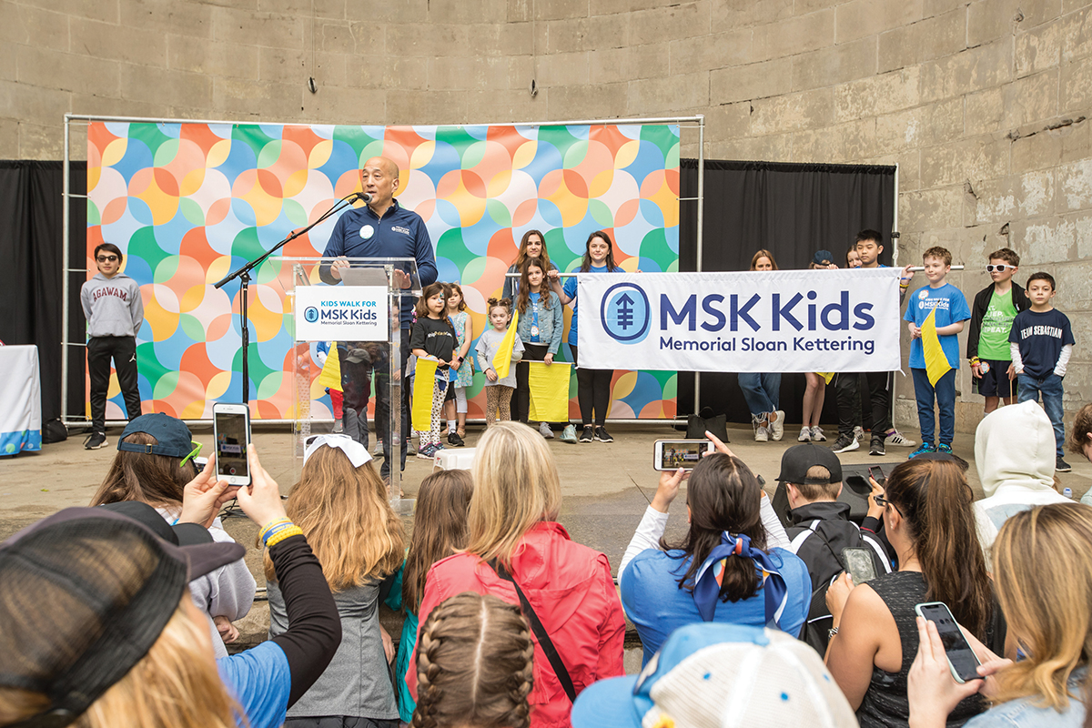 A man speaks at a podium in front of a crowd of kids