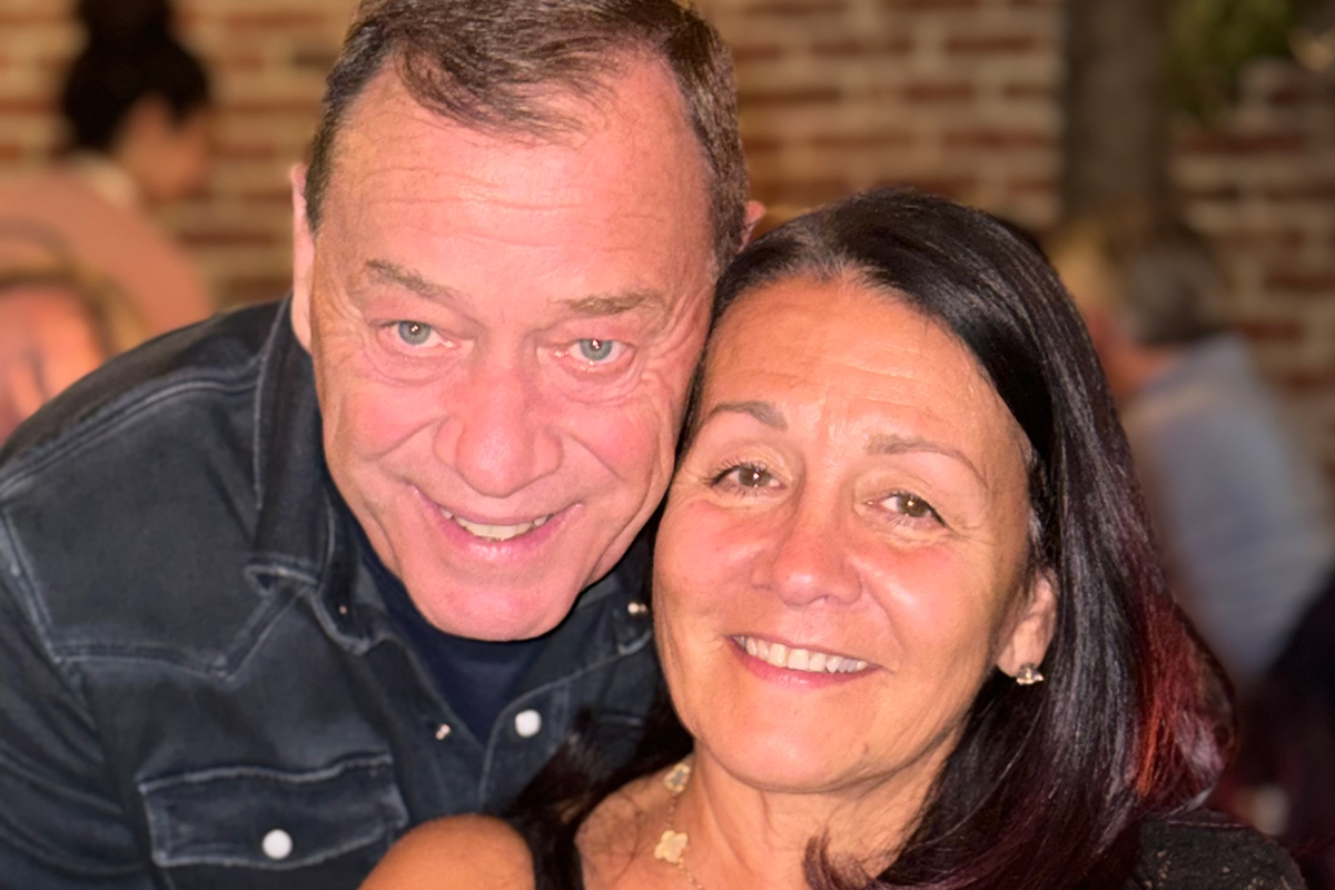 Man posing with wife, smiling.