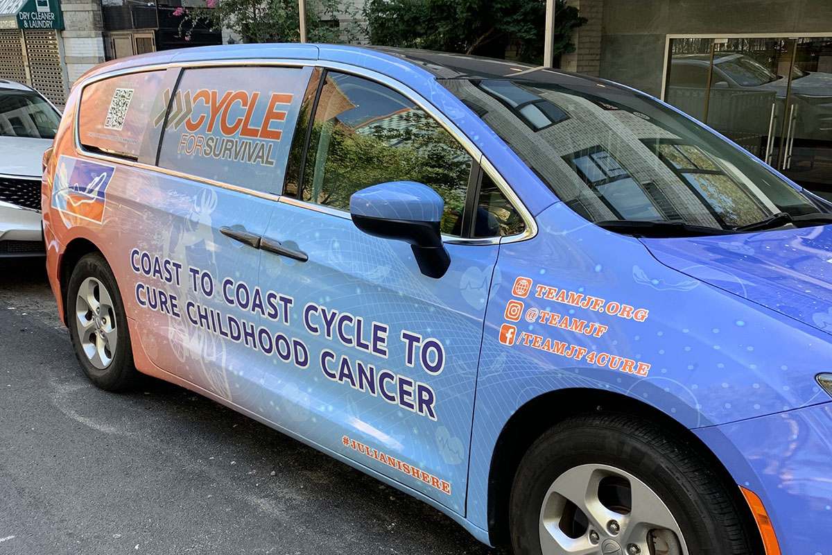 Blue van with Coast to Cost Cycle to Cure Childhood Cancer written on the side