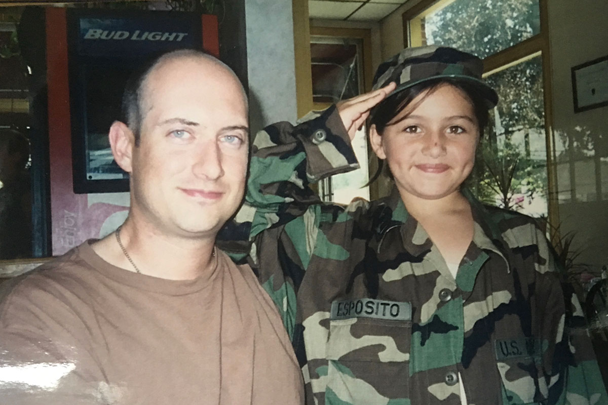 Hillary Esposito as a young child wearing camoflauge and posing with her father