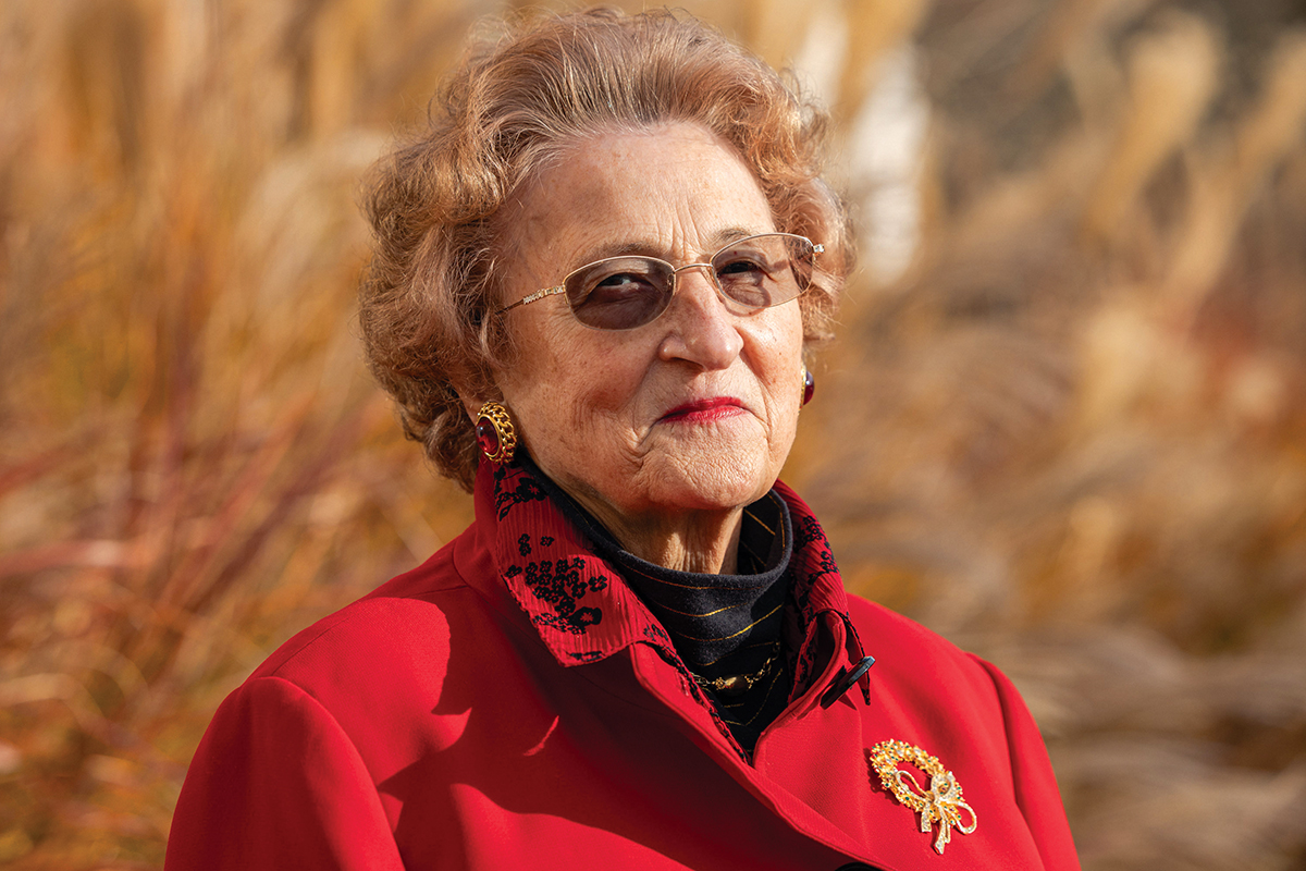 Woman, 74, in red coat and glasses.