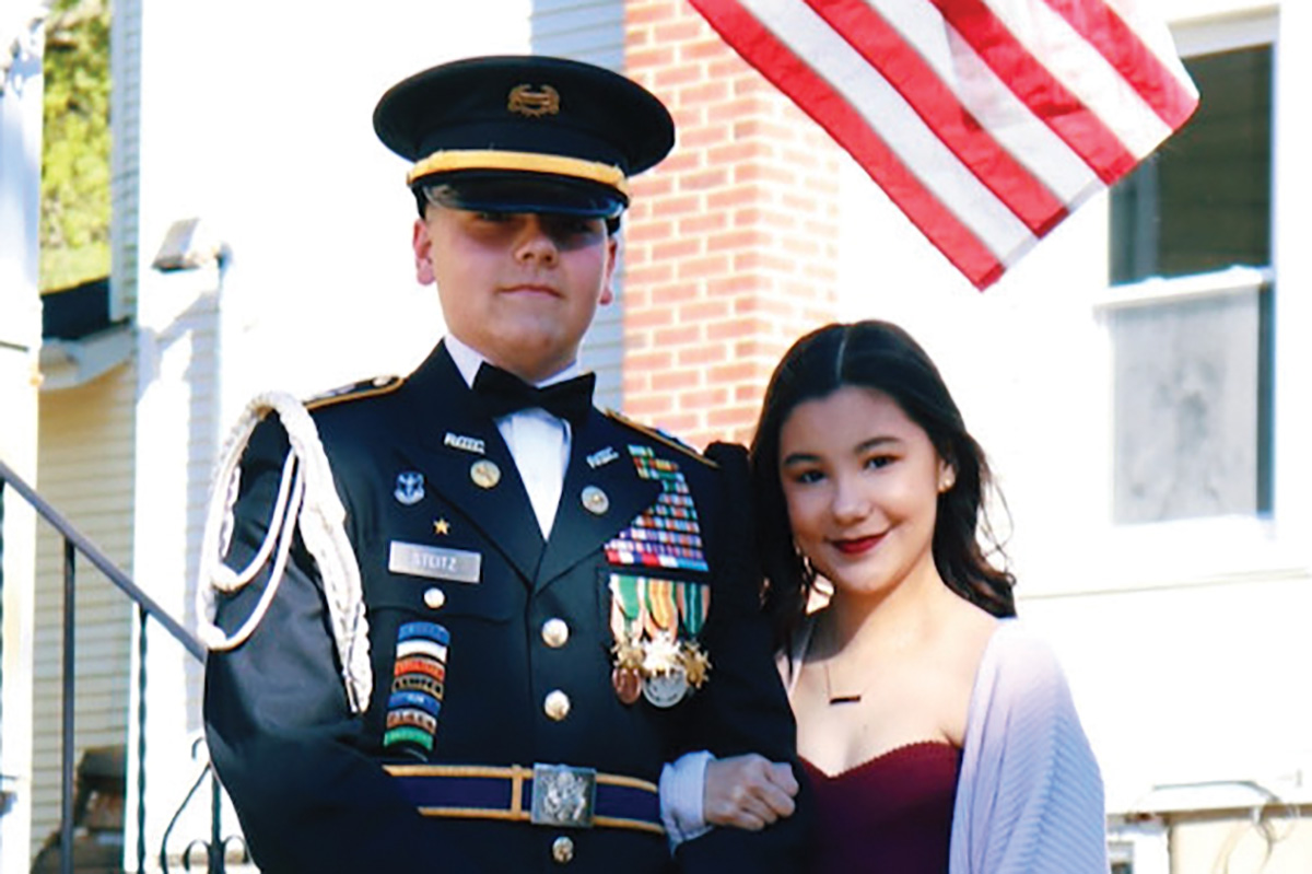 Anthony and Giovanna stand in front of a US flag