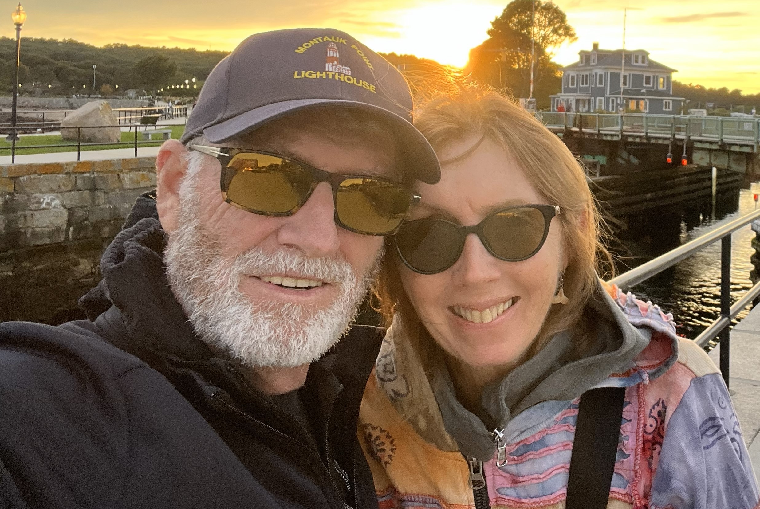Woman and husband smiling in front of sunset.