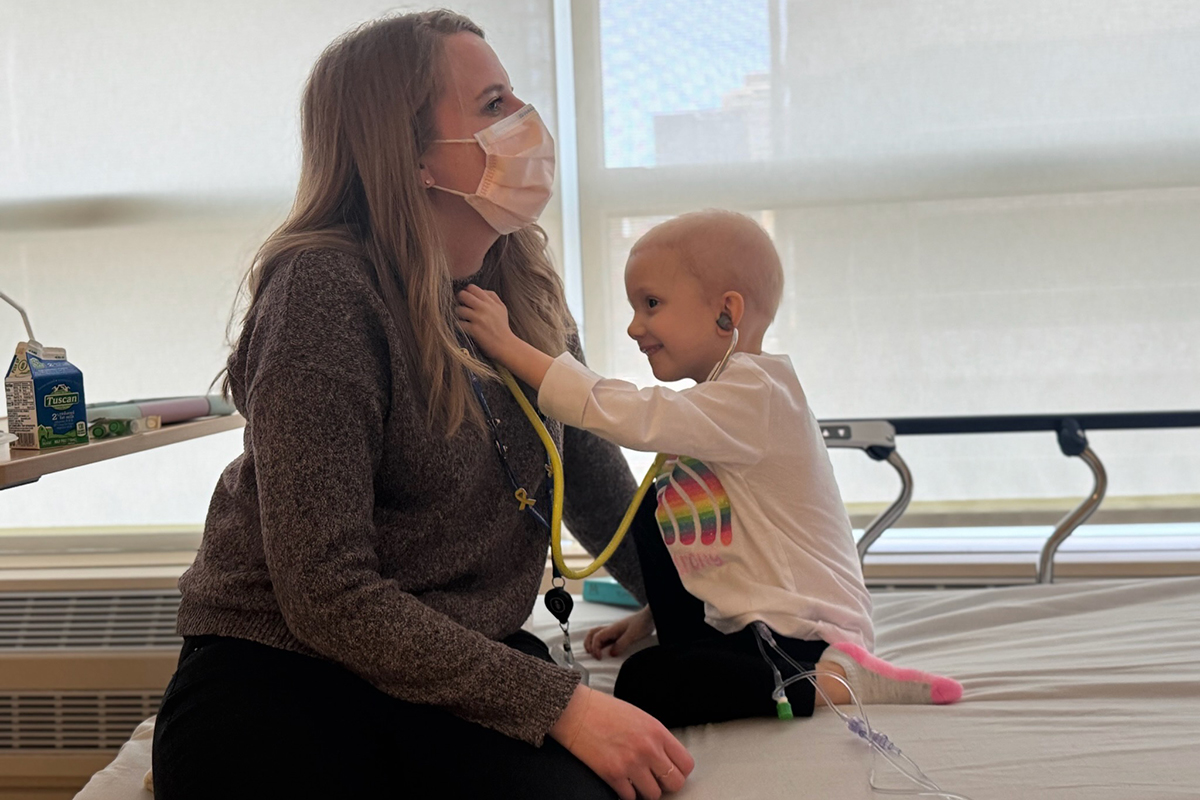 Sienna holds a stethoscope to nurse practitioner Talia Sauerhaft's chest