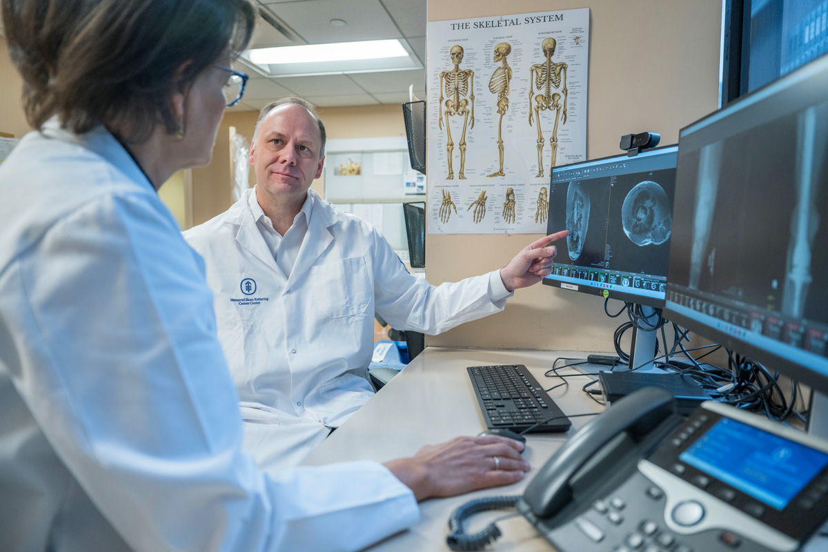 Damon Reed, Pediatric Hematologist-Oncologist reviewing an MRI of osteosarcoma with Carol Morris, MD, MS, Orthopaedic Surgeon.