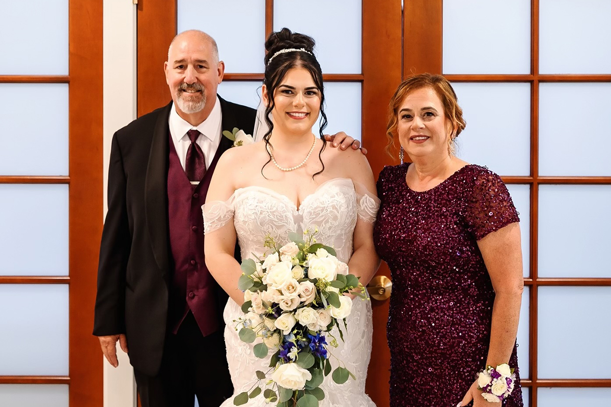 Michael with his wife and daughter. His daughter is in a wedding dr