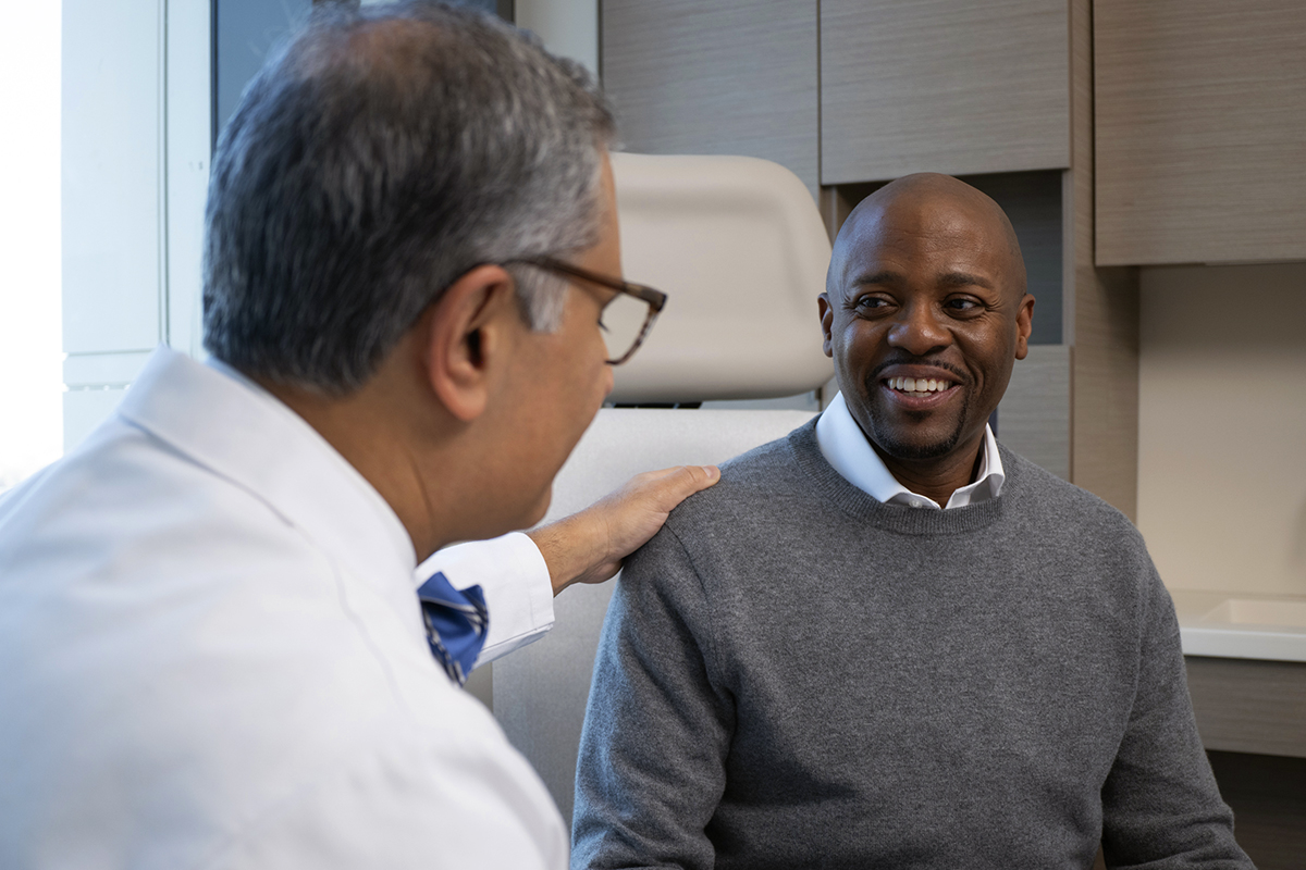 MSK patient Eddie Baynes listens smiling to his oncologist 