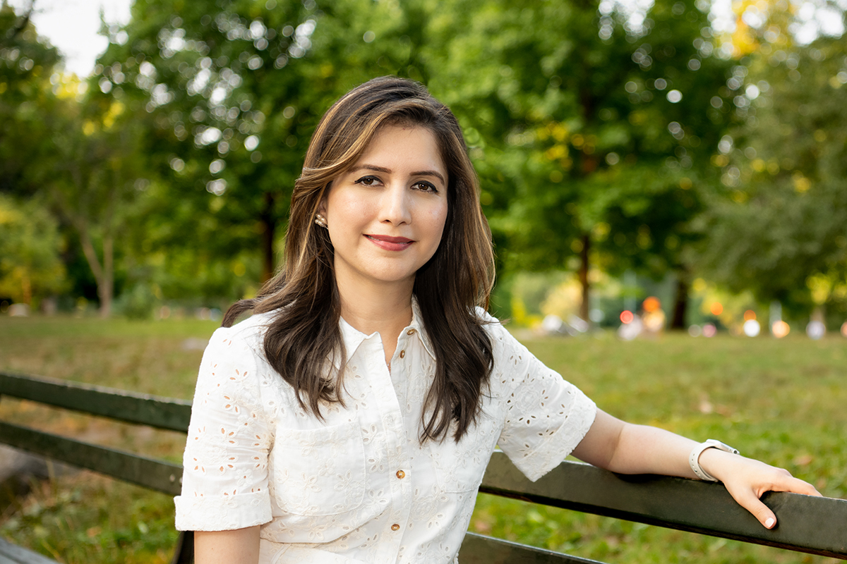 Sundas Hashmi sits smiling on a park bench in Central Park 