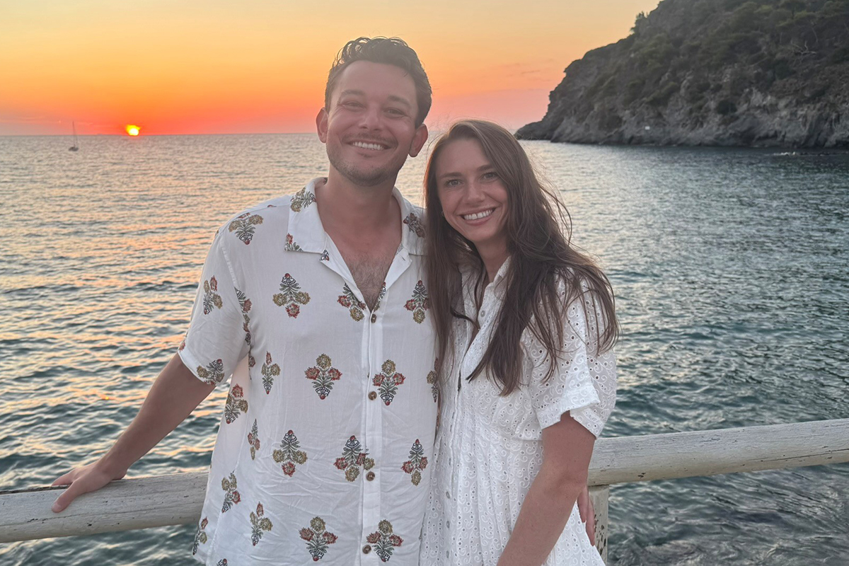 Adrianna Gildner and husband arm-in-arm smiling in front of a sunset in Italy.