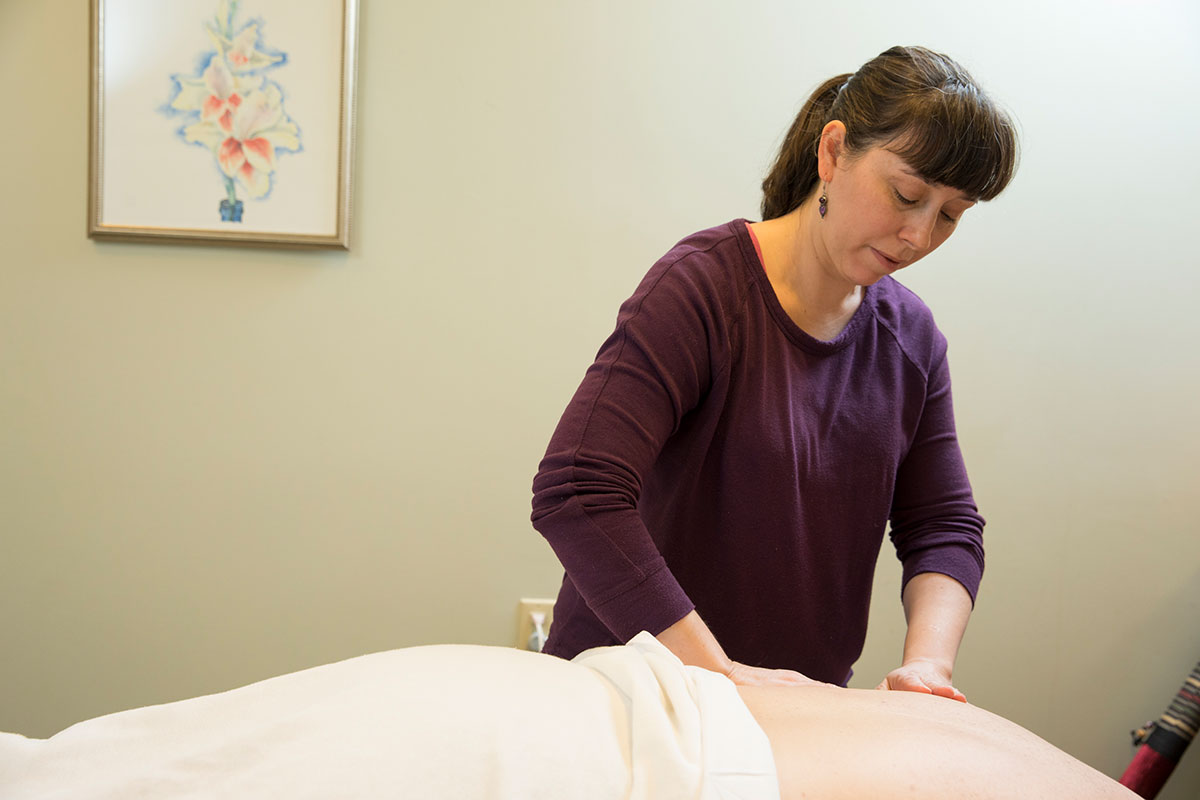 Woman massaging a patient laying on a table