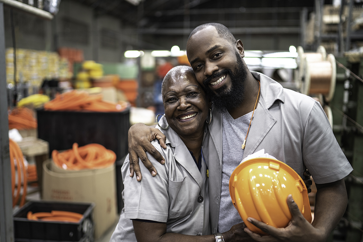 Black Female and Male Coworkers Smiling Warmly in Factory