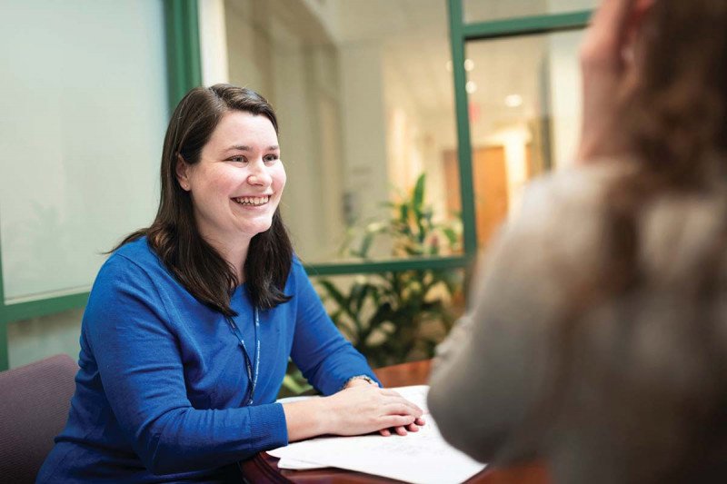 MSK genetic counselor, Meg Sheehan, sitting at a table with paper work while smiling at a female patient