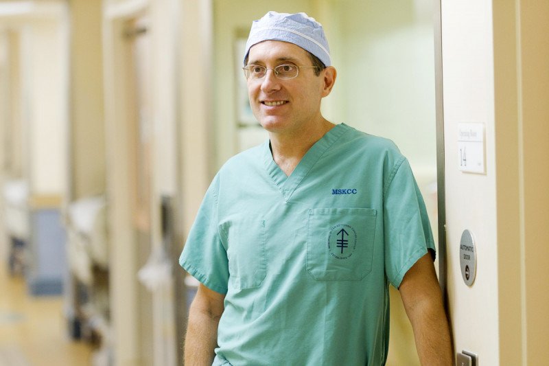 Ronald DeMatteo, Head of the Division of General Surgical Oncology at MSK, smiles at the camera while dressed in his scrubs.