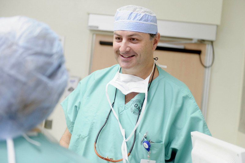 Surgeon and cervical cancer expert Nadeem Abu-Rustum dressed in surgical scrubs speaks to fellow doctor.