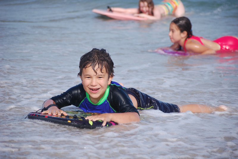 Smiling boy lying on board in the surf at the beach.