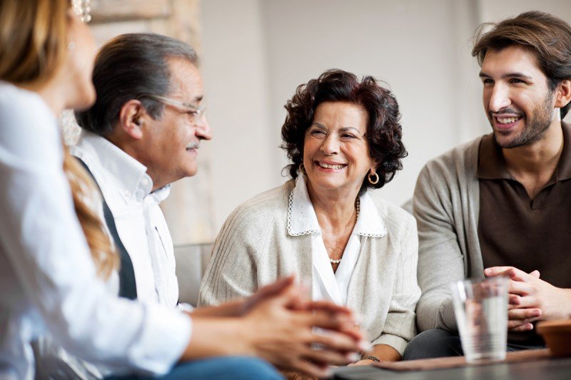 Photo of four people around a table smiling and conversing.