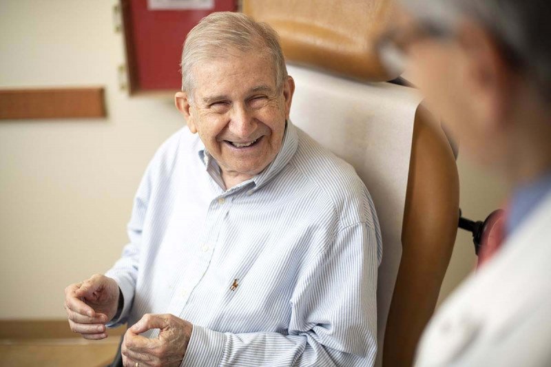 Smiling elderly man sitting in chair.