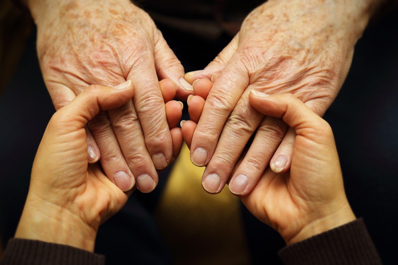 Young hands holding the hands of an older adult