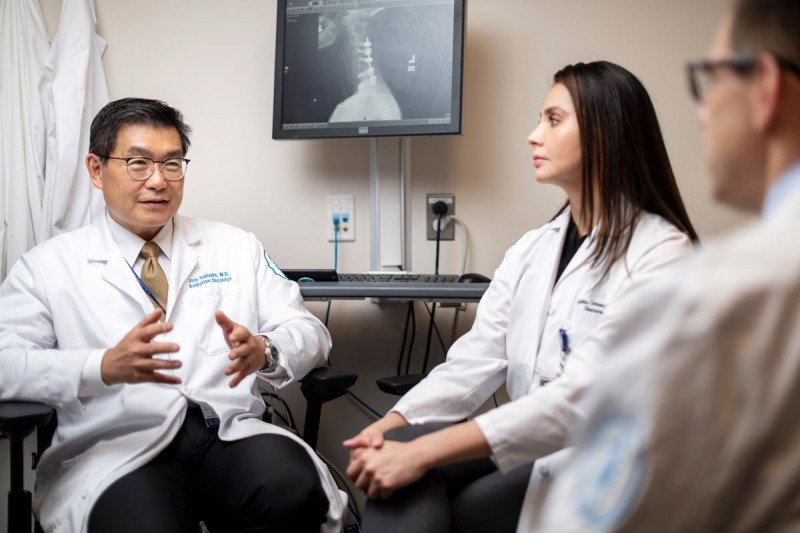 Radiation oncologist Josh Yamada and clinical nurse Cynthia Correa talking in an office.