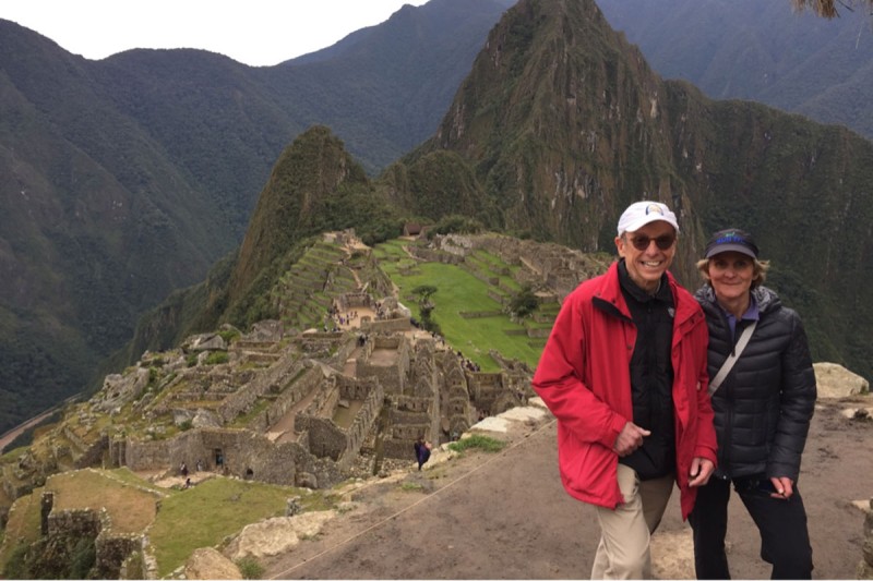 Husband and wife standing on a mountain at Machu Picchu in Peru, with the citadel in the background