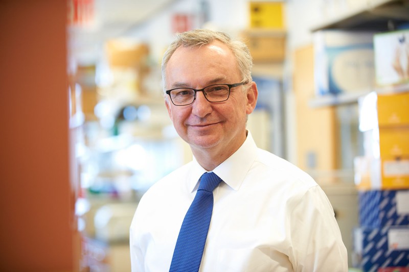 Head shot of doctor with glasses, white shirt, and blue tie in his lab.