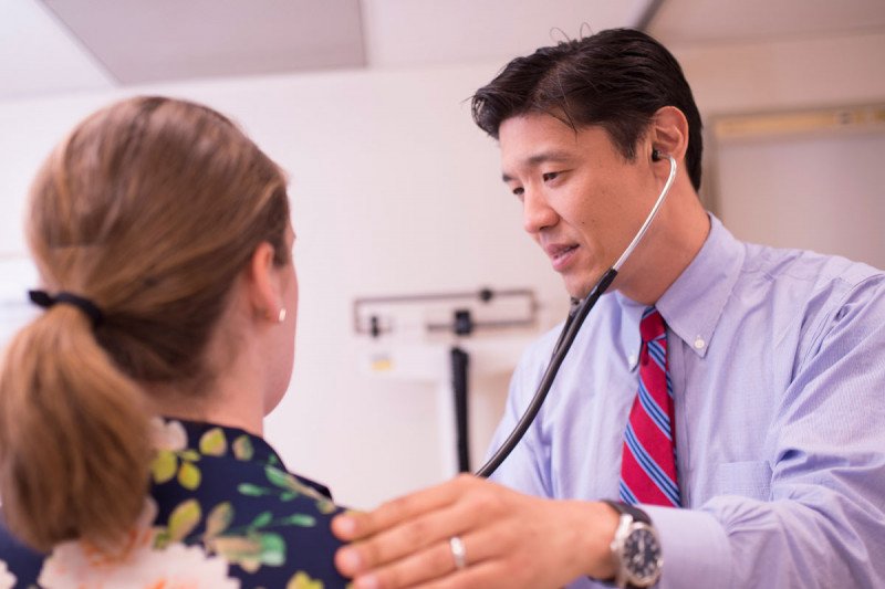 Memorial Sloan Kettering salivary gland cancer doctor, Alan Ho, examines a female patient using his stethoscope. 