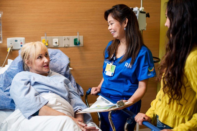 A nurse talks with a patient in a hospital bed