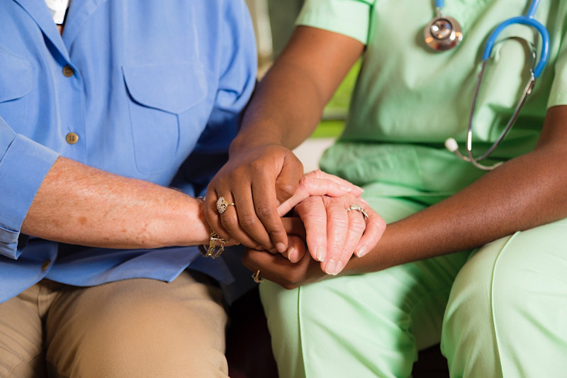 Closeup photograph of a nurse and patient holding hands