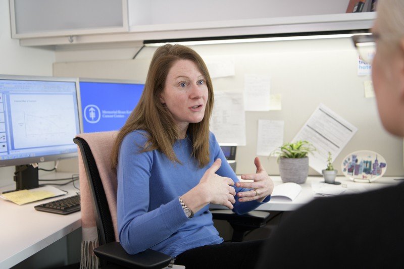 Woman sitting at her desk explaining something to someone off camera