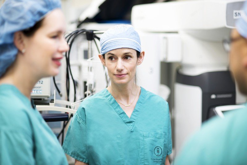 Gynecologic surgeon Kara Long Roche in green scrubs with two team members