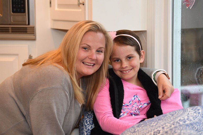 Young girl wearing pink sits with her mother