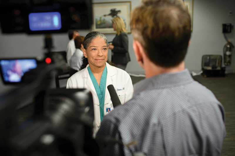Surgeon in a white coat being interviewed by a camera crew