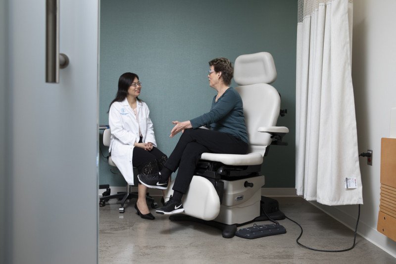 Breast medical oncologist Rui Wang (left) listens to a patient during an exam.   