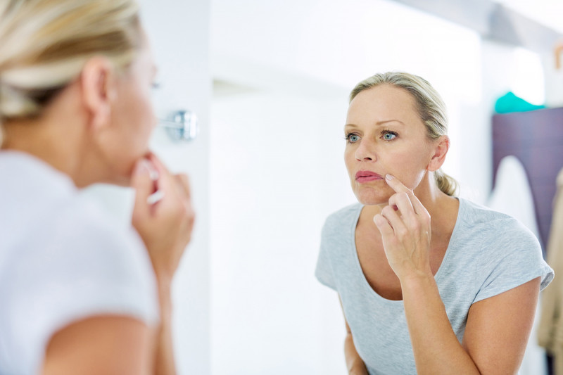 Woman examining her face for signs of cancer