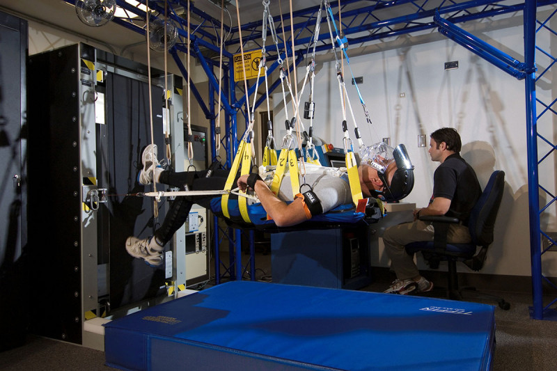 Man suspended with harnesses and walking on vertical treadmill