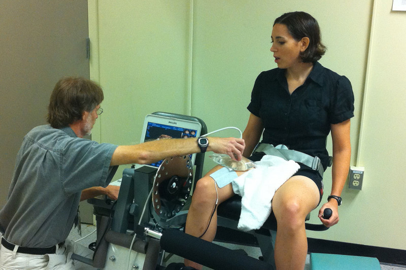 Woman exercising her leg while man reads a computer