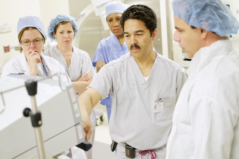 MSK Director of the Gastrointestinal Endoscopy Unit, Hans Gerdes (center), analyzes a screen with four other colleagues dressed in their scrubs.