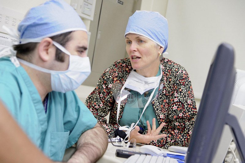 La cirujana especialista en melanoma Mary Sue Brady, hablando con un colega de MSK, con mascarillas y ropa quirúrgica antes de un procedimiento