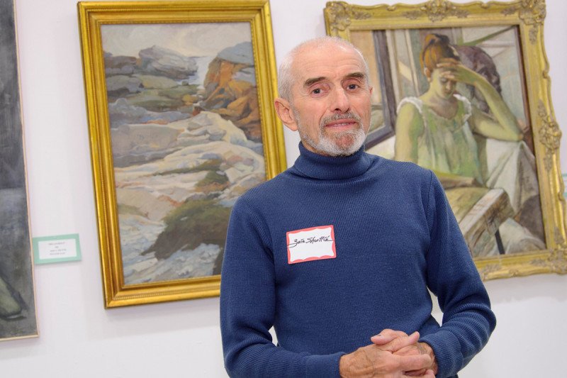 Zois Shuttie poses in front of some of his paintings at the Patient Art Show.