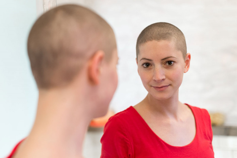 woman with shaved head in mirror