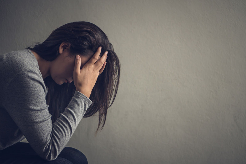 woman against grey background with her head in her hands