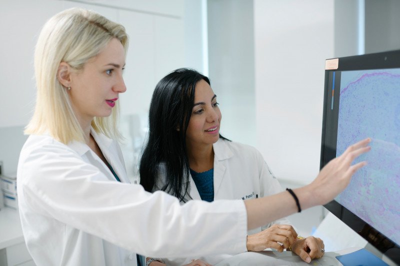 Dermatologist Alina Markova and hematologic oncologist Doris Ponce work at a computer showcasing GVHD cells together.