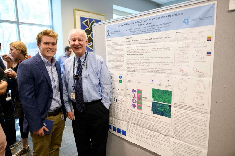 Two men pose in front of scientific poster
