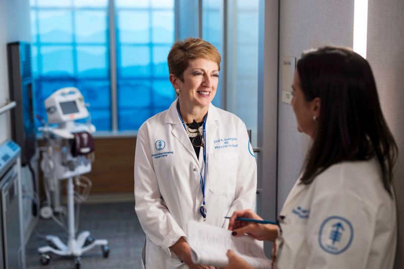 Neuro-oncologist and MSK Physician-in-Chief Lisa DeAngelis speaks to colleague in a hospital room.