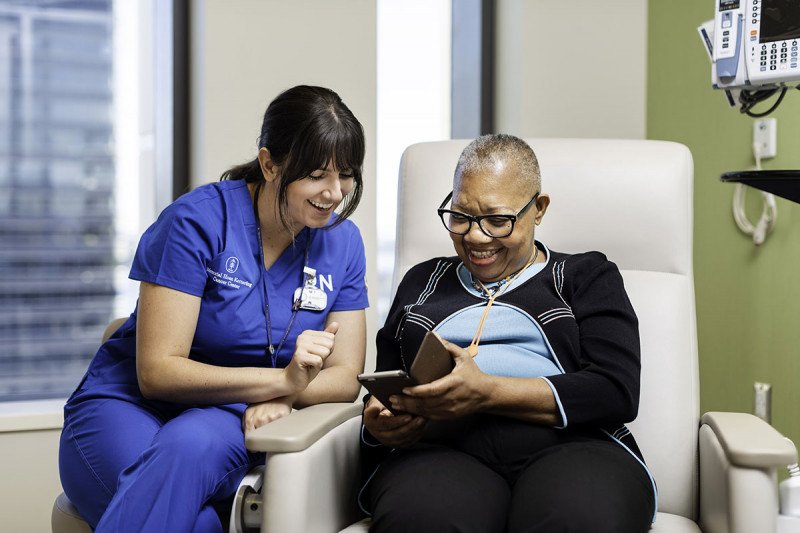 A female nurse talks with a female patient, who is sitting in an exam chair